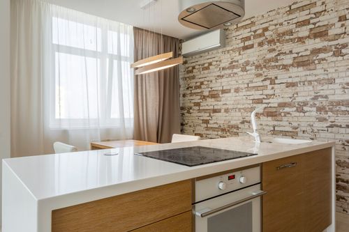 Free A modern kitchen interior featuring a sleek countertop and brick accent wall for a cozy atmosphere. Stock Photo