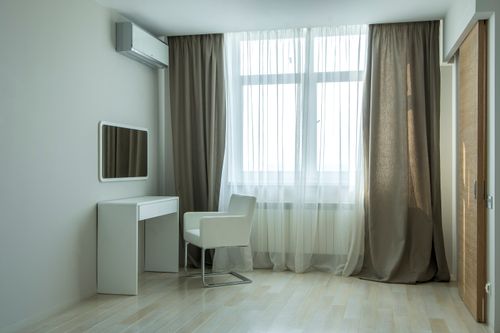 Free Sleek minimalist room with white desk, chair, and large window with sheer curtains. Stock Photo