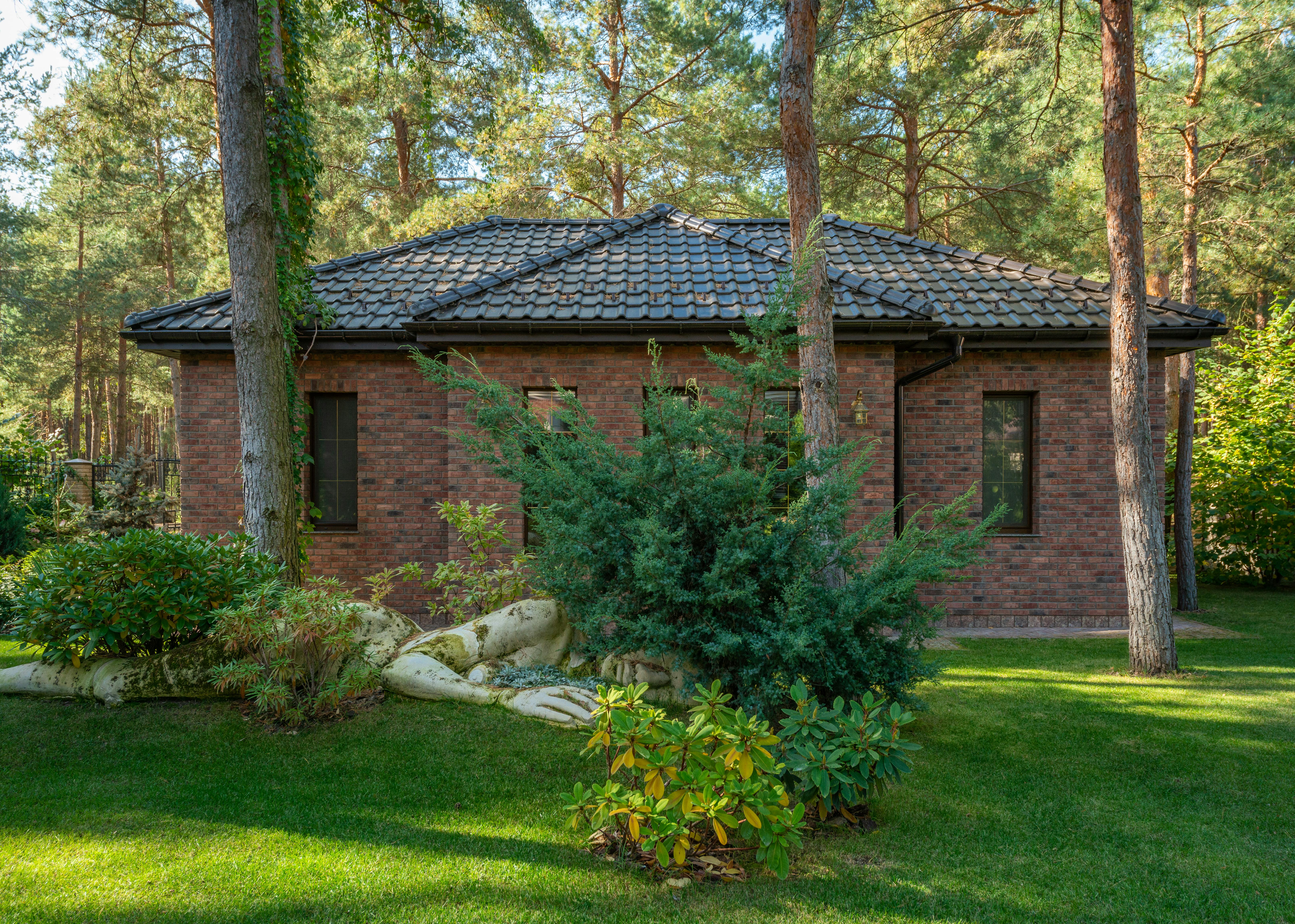 A small brick house in the middle of a forest surrounded by trees.