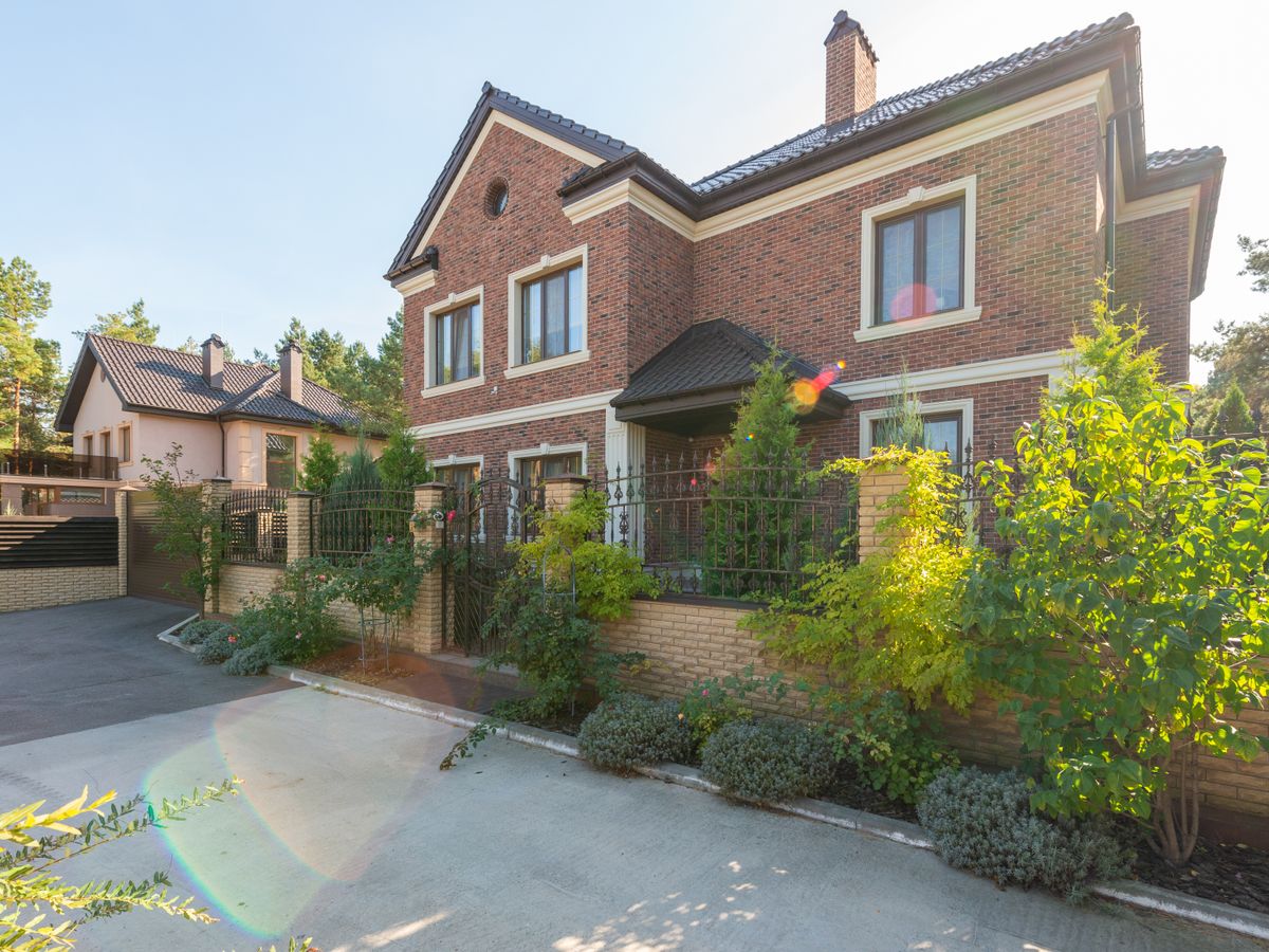 Brick home framed by mature landscaping and a driveway, typical of the older Waxahachie, TX properties where dense planting raises pest pressure