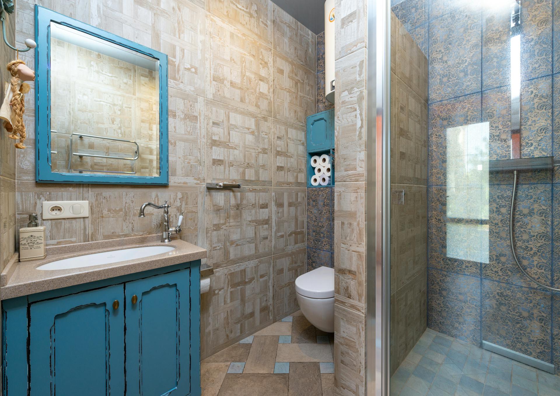 Charming bathroom with blue cabinet, tiled shower, and stylish vanity for a cozy interior feel.