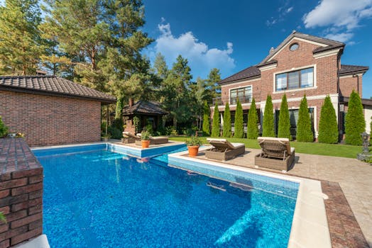 Beautiful brick residence with swimming pool, surrounded by trees and greenery.