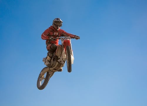 A Low Angle Shot of a Person Wearing Helmet while Riding a Motorcycle in the Air