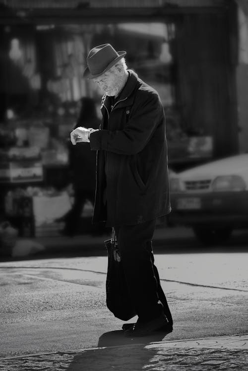 An Elderly Man Standing on the Street while Looking at His Watch