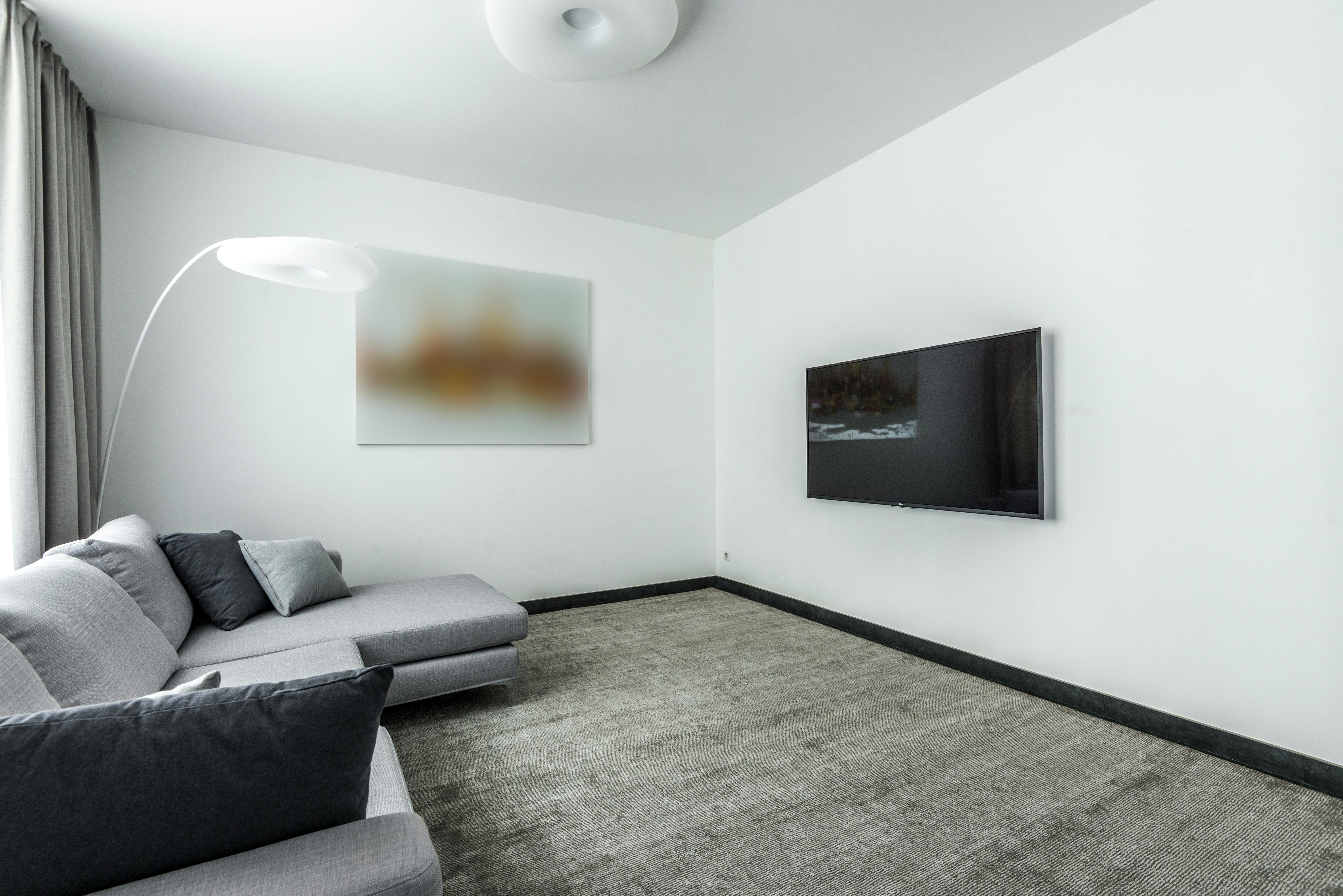 Modernes Wohnzimmer mit frisch weiß gestrichener Wand, Malerrolle und sauberer Kante zur Decke