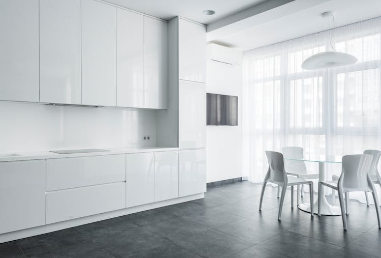 White Chairs And Glass Table Near White Cabinets