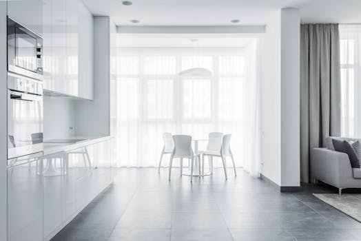 Bright minimalist dining area with white furniture and modern kitchen design.