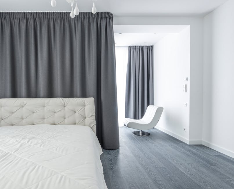Helles, minimalistisches Schlafzimmer mit Leinenbettwäsche, heller Wandfarbe und leichtem Vorhang für kühles Raumgefühl