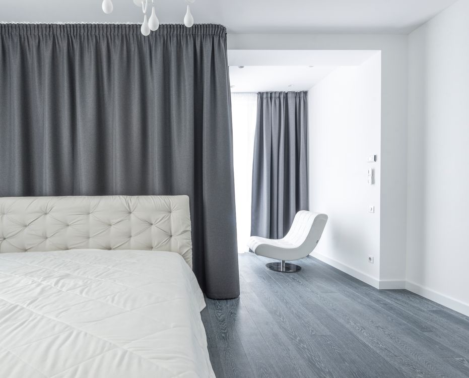 Cozy minimalist bedroom with soft grey curtains and simple bedding — the bedroom sanctuary that less furniture creates