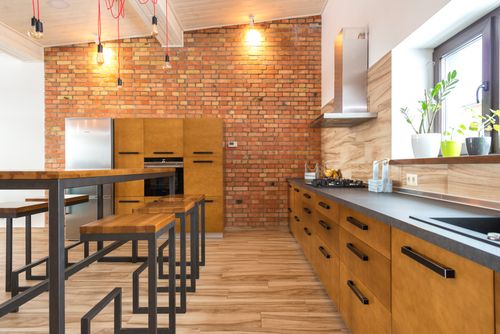 Free Contemporary kitchen featuring brick wall, wooden cabinets, and sleek design elements with ample natural light. Stock Photo