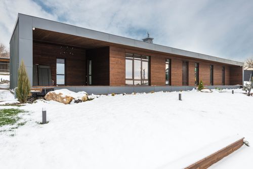 Free A sleek modern wooden house stands surrounded by a snowy winter landscape, showcasing contemporary architecture. Stock Photo