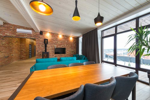 A Wooden Tables with Chairs Near the Living Room with Television on the Wall