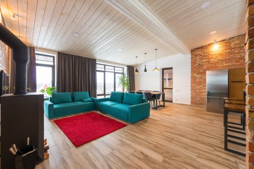 Free Spacious and stylish living room featuring a teal sofa, brick wall, and modern design elements. Stock Photo