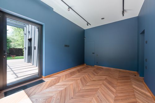 Free Contemporary interior room with blue walls, wooden flooring, and large glass door. Stock Photo