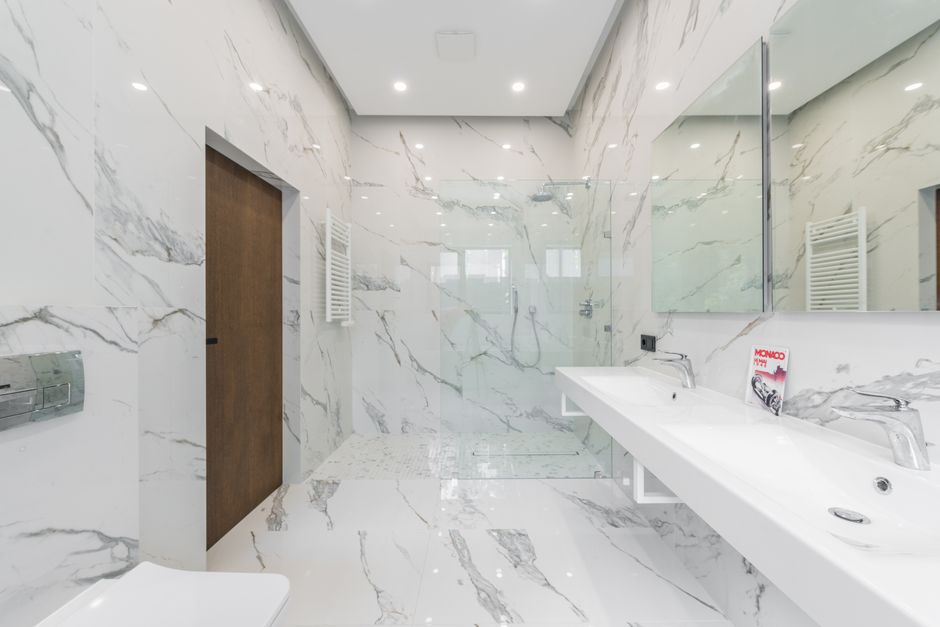 Modernes Badezimmer mit hellen Wandpaneelen in Steinoptik und schwarzen Armaturen, saubere Fugen und klare Linien