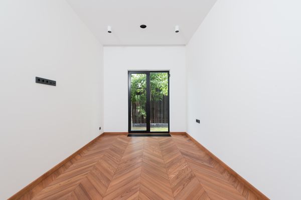 Empty room with chevron wood floor and glass doors