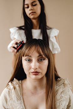 Portrait of a teenager brushing her mother's hair in a studio setting.