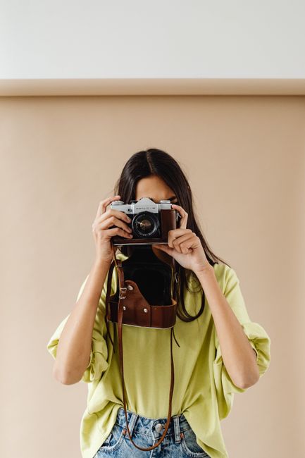 Portrait of a woman holding a vintage camera, ready to capture perfect moments indoors.