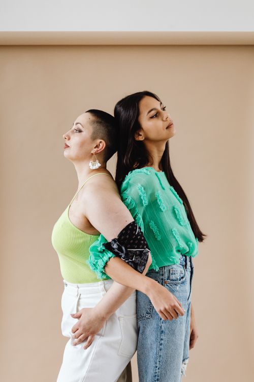 Free Two fashionable women standing back to back, showcasing casual style and diverse beauty. Stock Photo