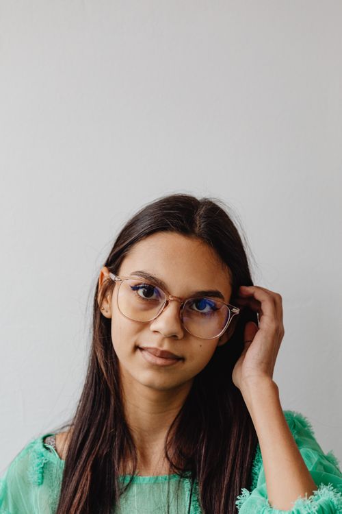 Free Young woman with eyeglasses and long brown hair posing against a white background. Stock Photo