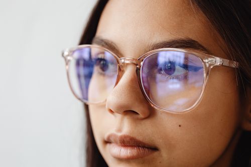 Free Intimate close-up portrait of a young woman wearing eyeglasses, reflecting light. Stock Photo