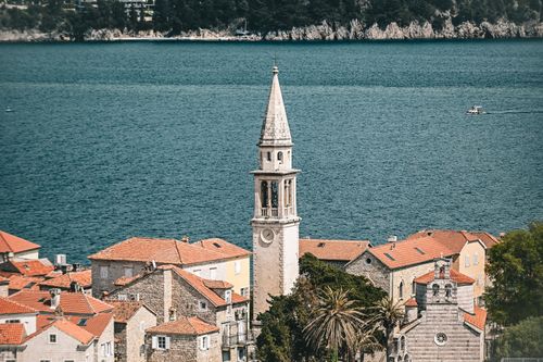 Free A picturesque coastal town with a prominent stone tower and red-tiled roofs by the sea. Stock Photo