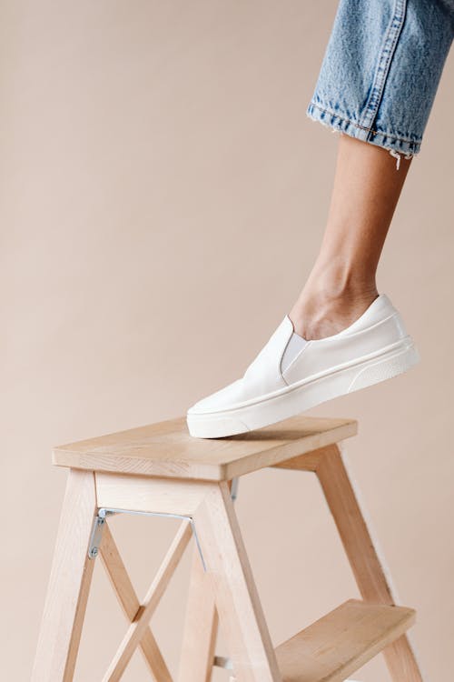 Person Wearing White Shoes Using a Stool