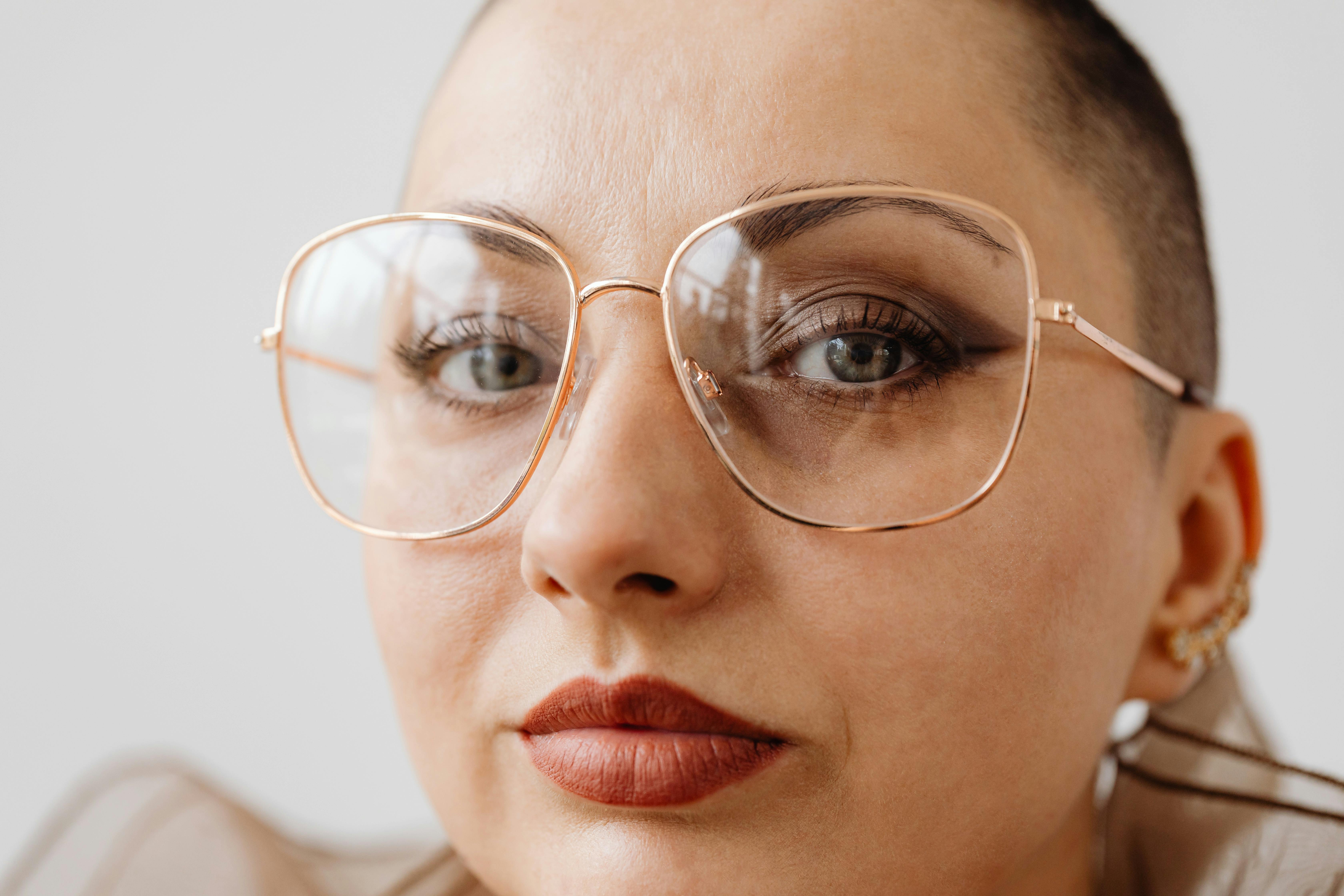 Elegant close-up portrait of a confident woman in stylish glasses against a neutral background.