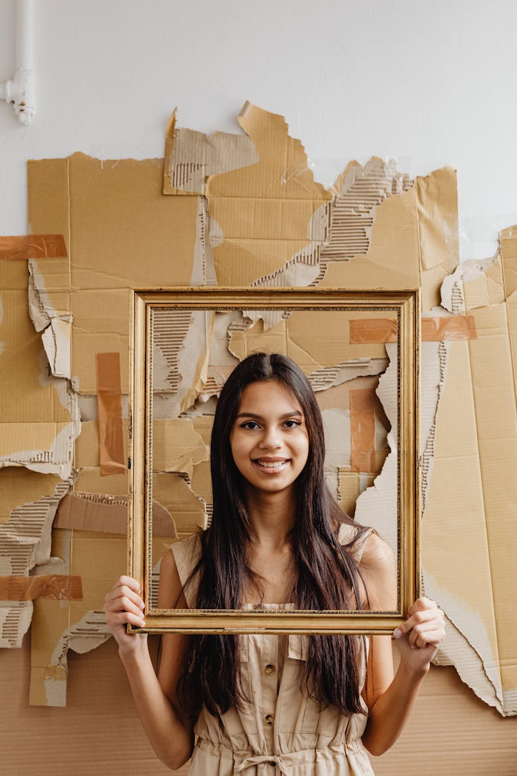 Portrait Of Smiling Woman Holding Gold Frame