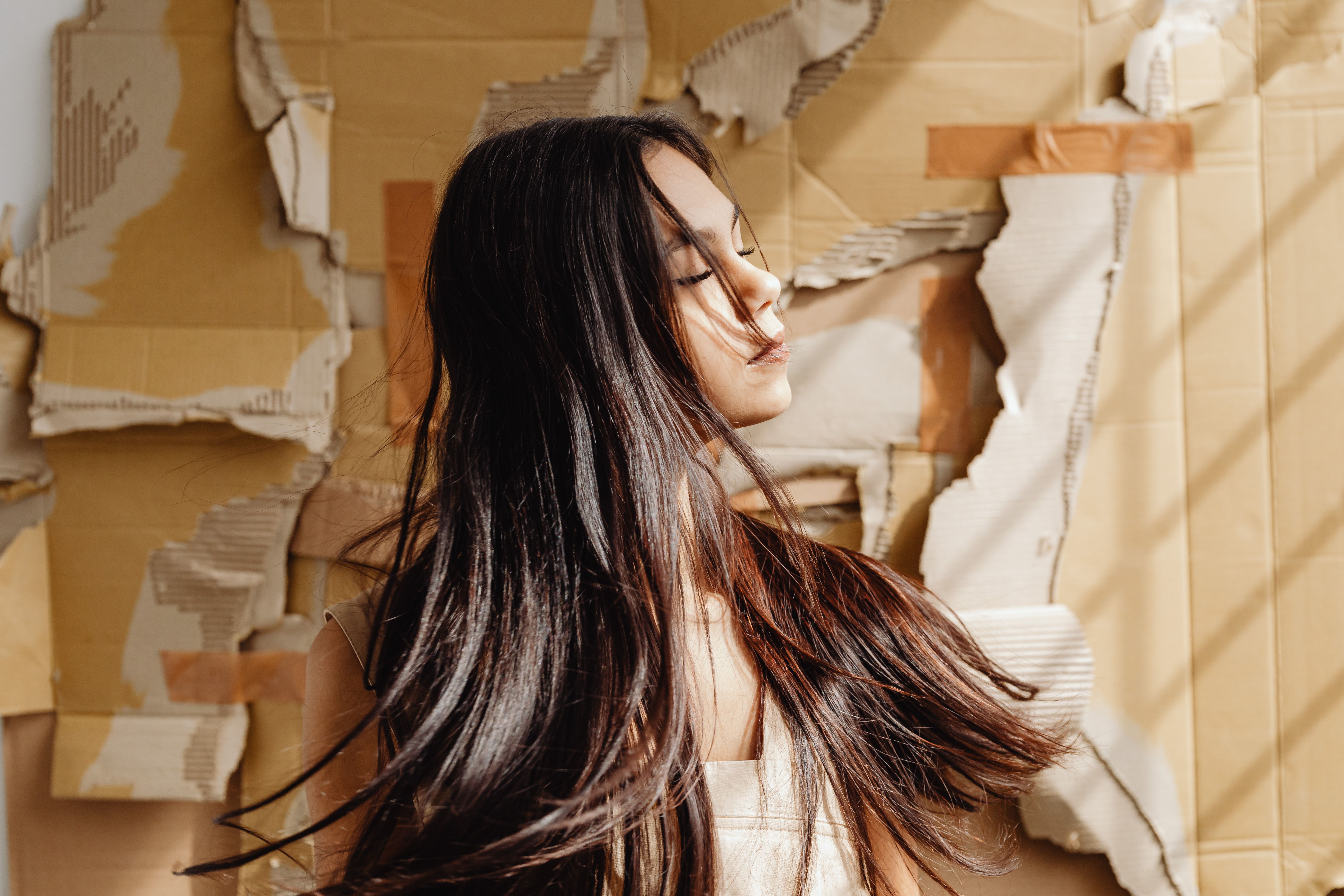 Portrait of a young woman with long hair against a textured cardboard background. Artistic and modern style.