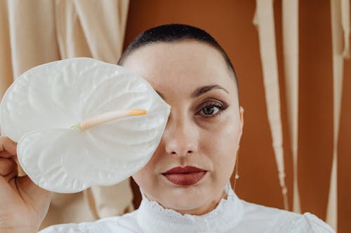 A Woman Covering Her Eye with a White Anthurium Flower