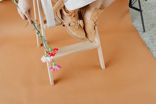 A Person Sitting on a Wooden Ladder Holding Flowers