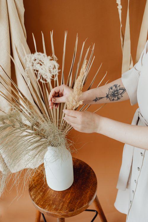 Free Elegantly styled dried floral arrangement in a ceramic vase on a wooden stool. Stock Photo