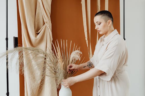 A Woman Arranging Dried Grass on a Ceramic Vase
