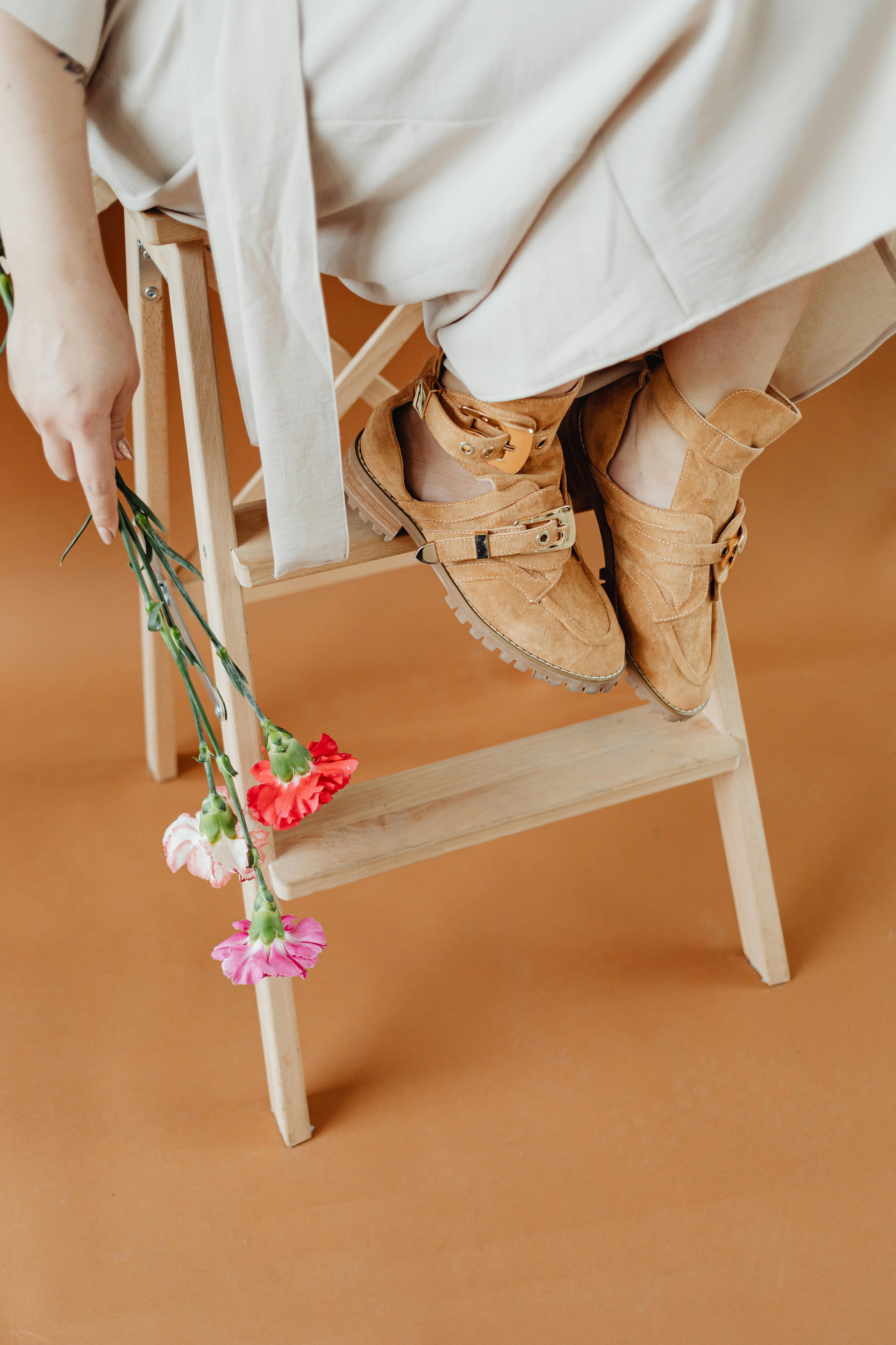 person wearing brown shoes holding flowers