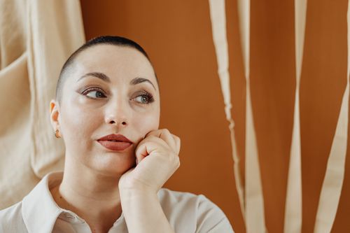Free Thoughtful woman with short hair in a serene indoor setting, featuring neutral tones. Stock Photo