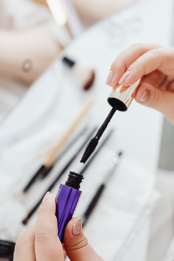 Mascara wand and eye makeup close up on beige