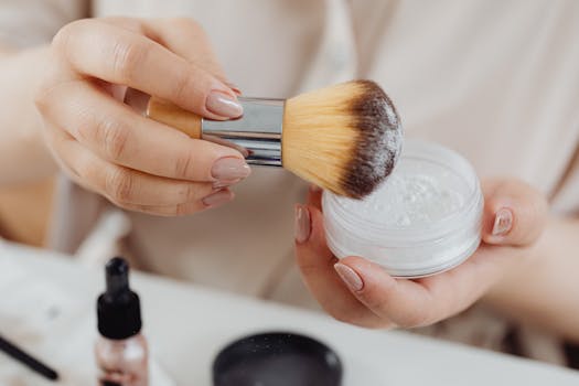 Detailed close-up of a makeup brush and powder, showing hands holding the products. Perfect for beauty concepts.