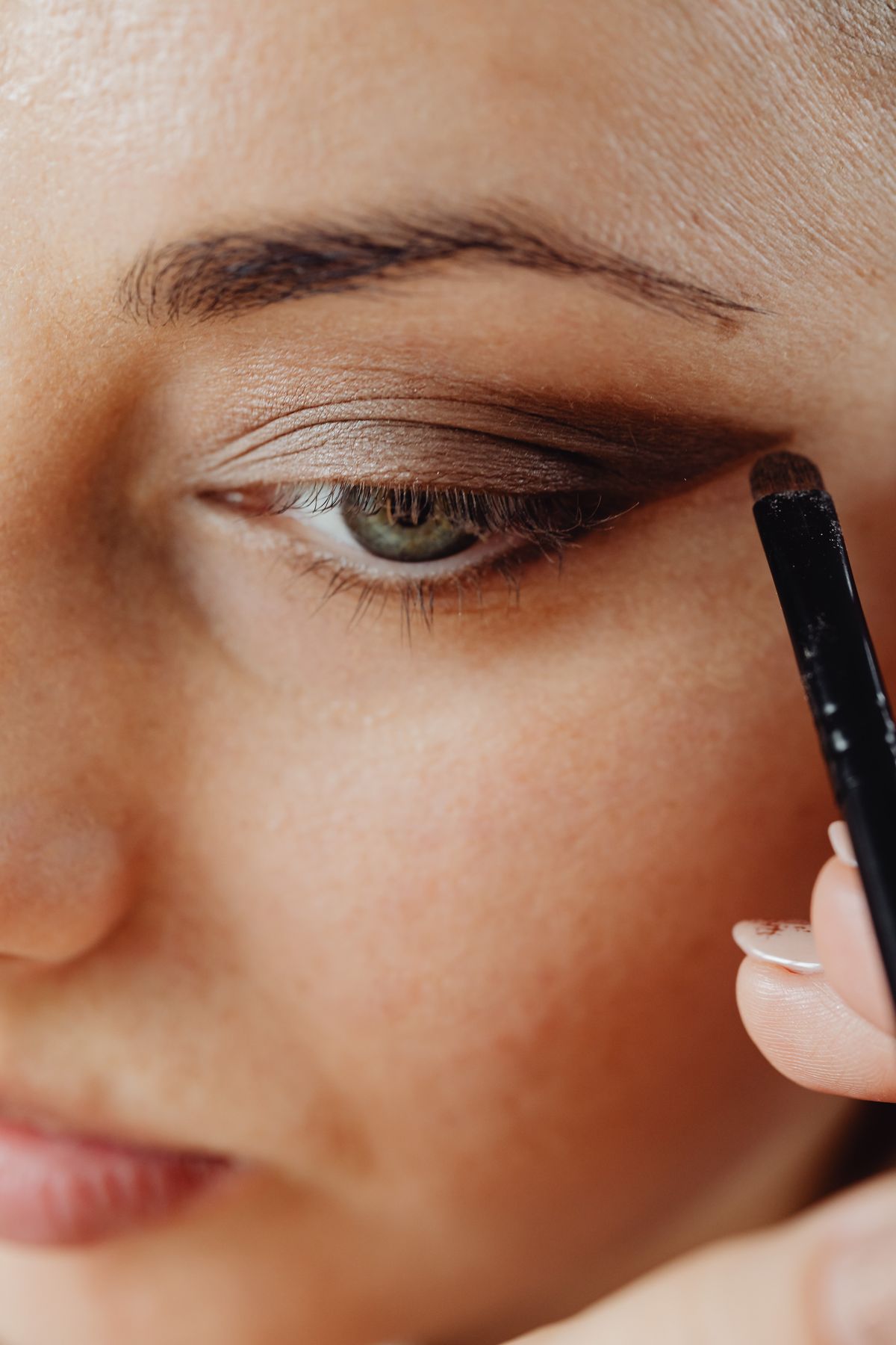 Close-up of brown eyeshadow being applied with a brush