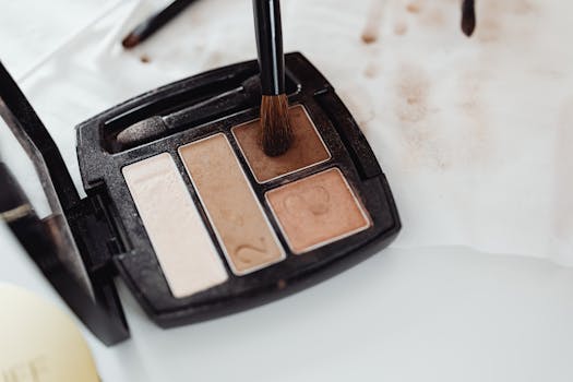 Close-up of a makeup eyeshadow palette in neutral shades with a brush touching the product surface.