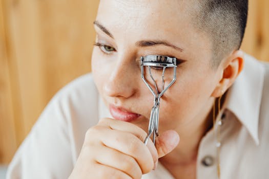 Woman using an eyelash curler for makeup application at home.