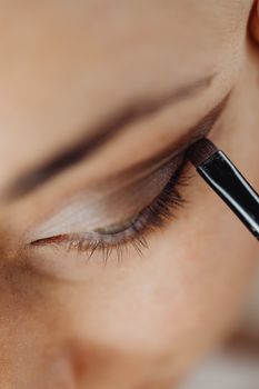 Detailed close-up of eyeshadow being applied with a makeup brush on eyelid.