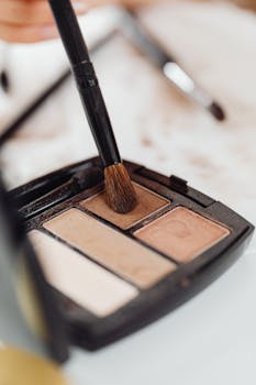 A detailed shot of a makeup palette with a brush applying eyeshadow, perfect for beauty and cosmetics themes.