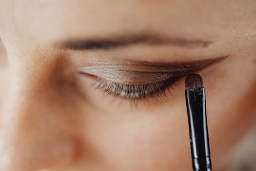 Detailed close-up of an eye being carefully enhanced with eyeshadow using a makeup brush.
