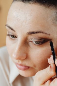 Detailed close-up shot of a woman applying eyeshadow with a makeup brush for a beauty routine.