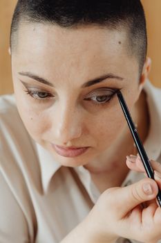 A woman in a close-up view applying eyeshadow with a brush indoors.