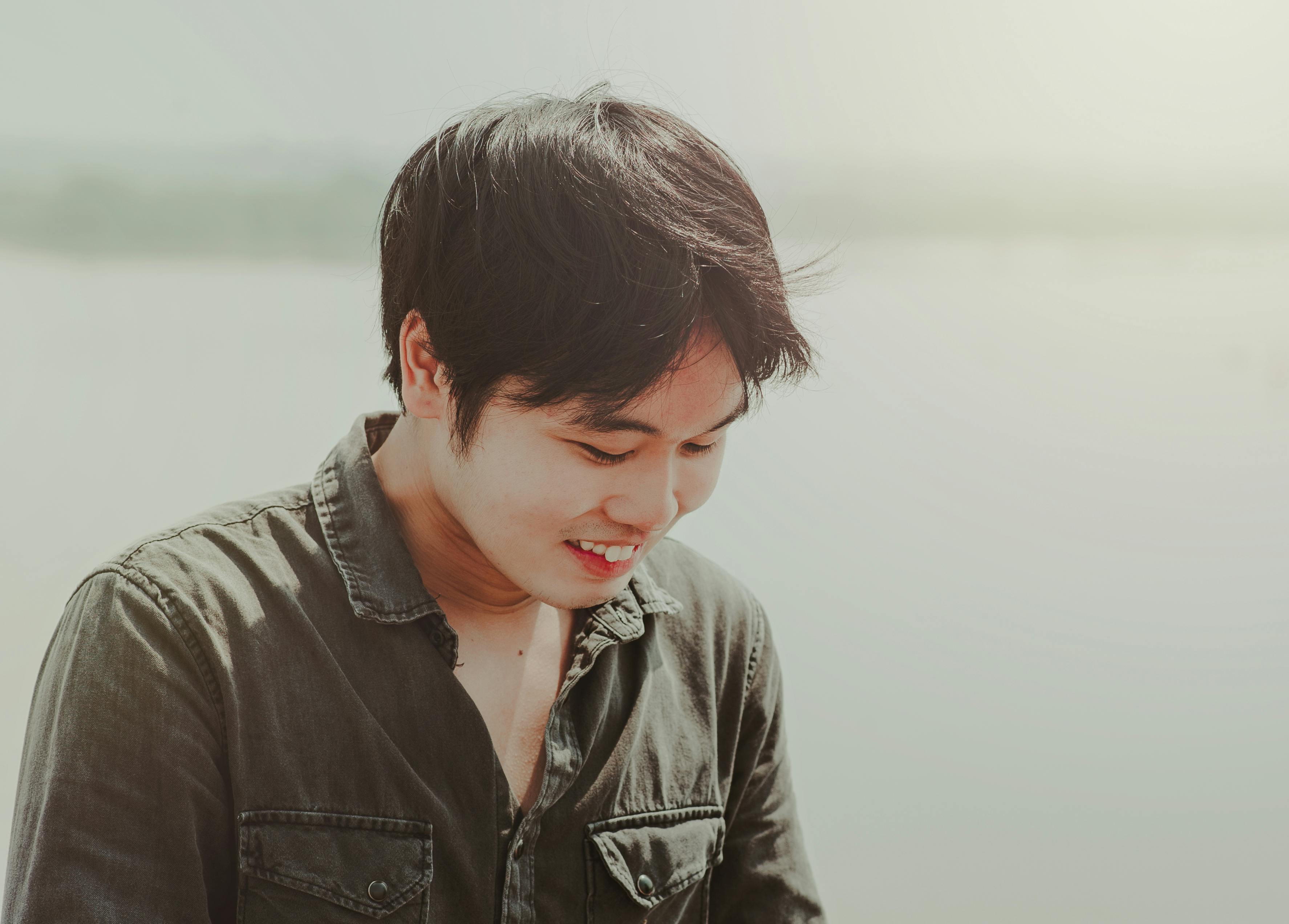 这是一张在柔和阳光下微笑的年轻人的坦率户外肖像