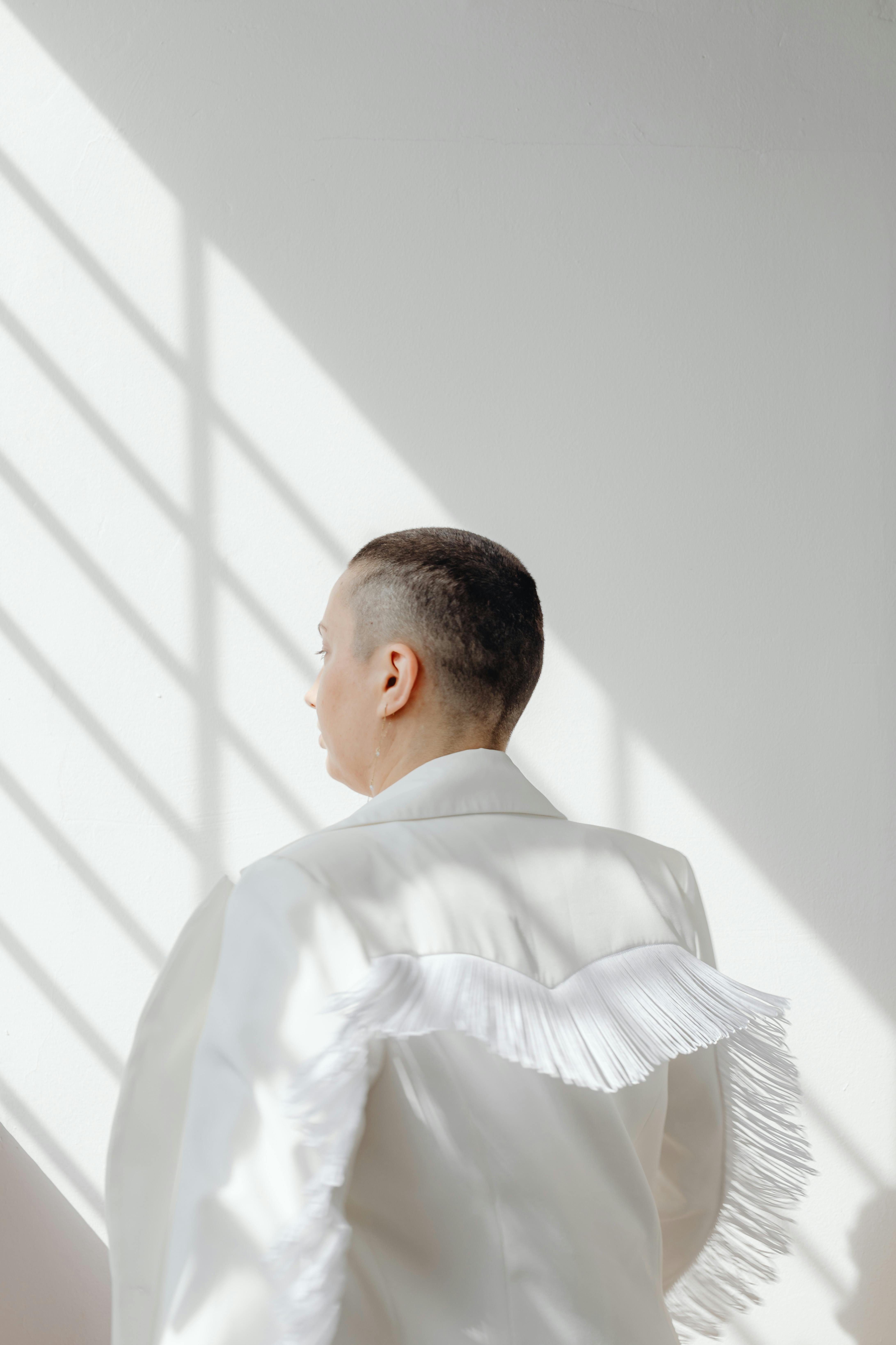 Silhouette of a woman with short hair in a white jacket against a bright background.
