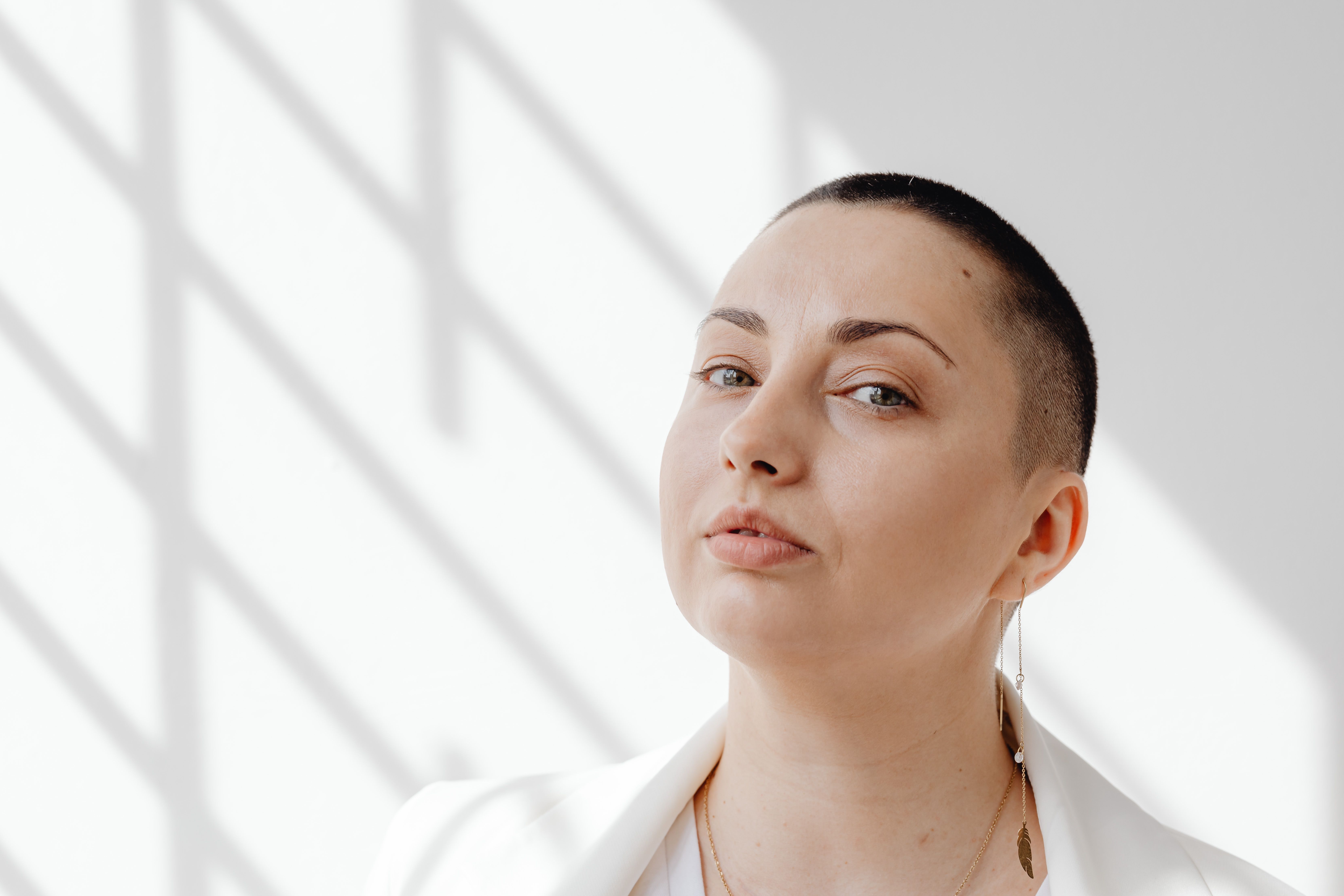 Portrait of a confident woman with short hair against a light and shadow background.
