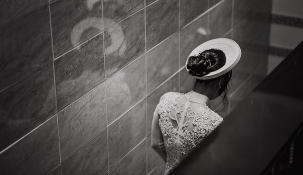 一名女子身穿蕾丝连衣裙，优雅地站在室内，身影映照在瓷砖墙上